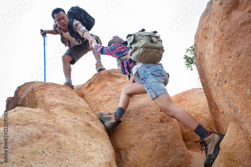  Team of climbers man and woman help each other on top of mountain, climbing hiking together, Young tourists with backpacks,
