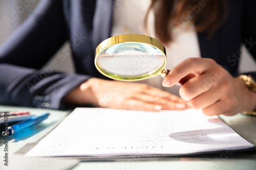 Businesswoman Looking At Contract Form Through Magnifying Glass