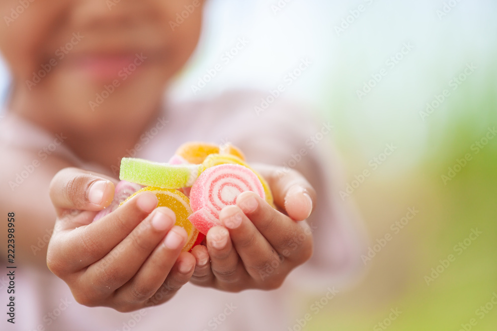 Cute asian child girl holding jelly candies in hand and sharing to other