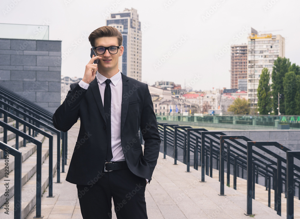Young businessman walking on the street and talking on the phone Young businessman walking on the street and talking on the phone