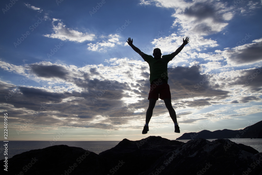 Man jumping on cliffs in sunset Man jumping on cliffs in sunset
