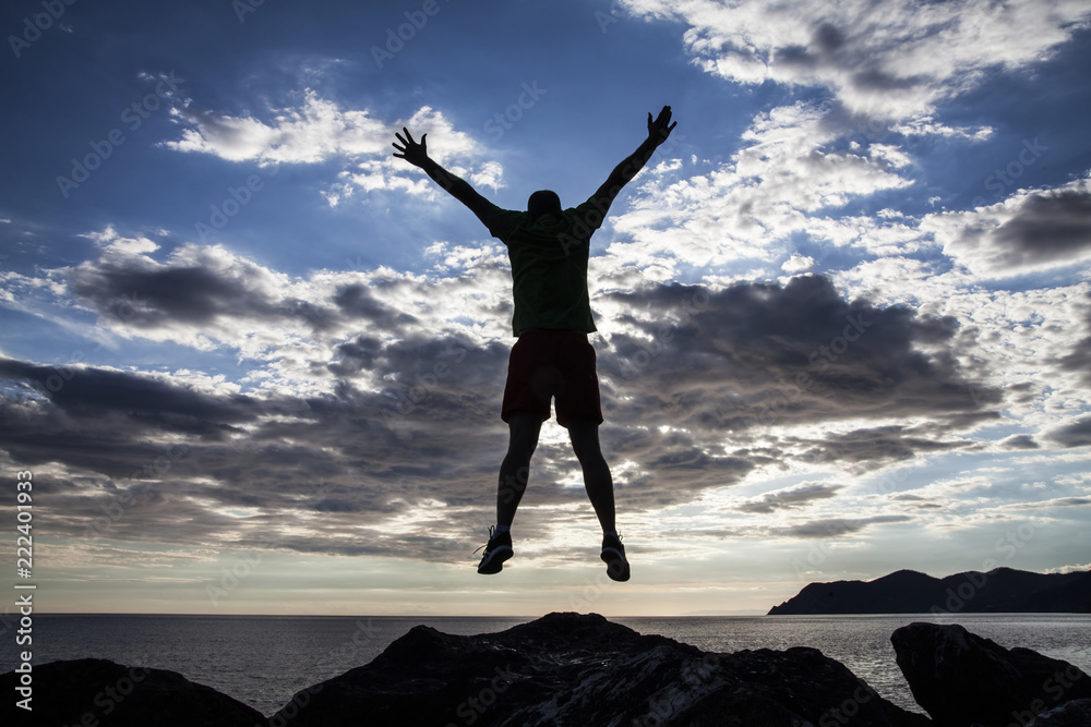 Man jumping on cliffs in sunset Man jumping on cliffs in sunset