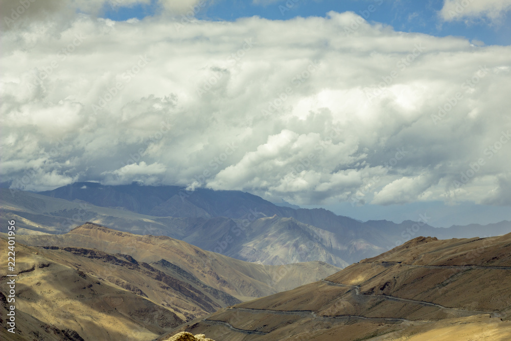 road in mountain valley with shadows from the clouds