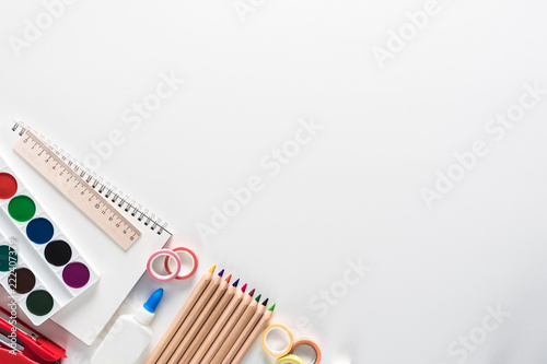 Top view over a notebooks  paints  pencils  glue  tapes on a white background. Back to school concept. Office supplies flat lay