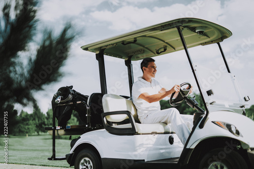 Young Man in White Shirt using Cart on Golf Field.