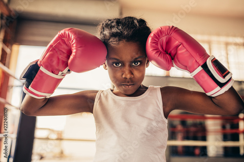 Boxing kid wearing gloves standing in a boxing gym