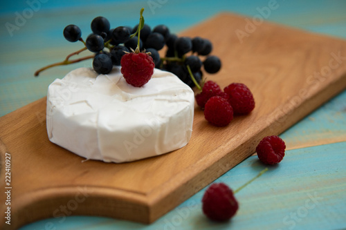 cheese camembert with raspberries and grapes on table