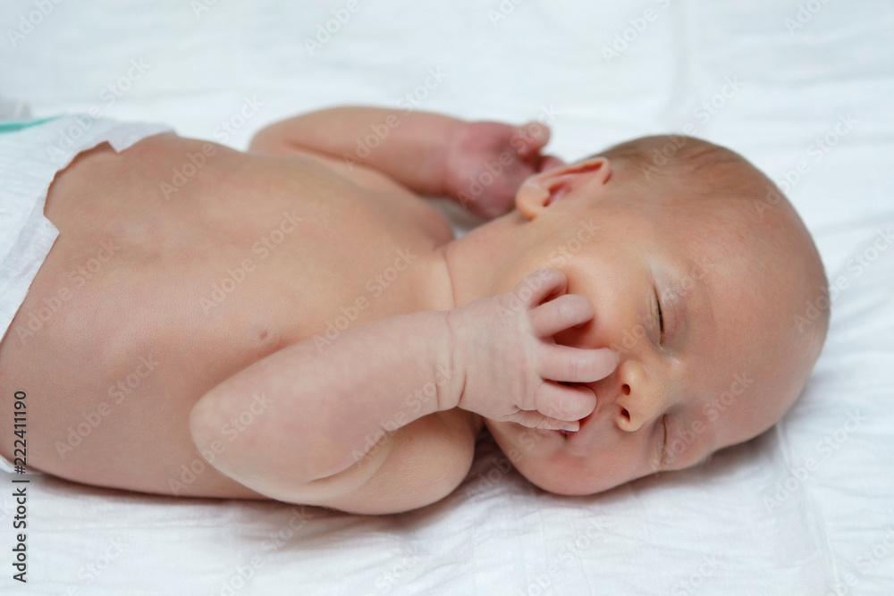 The baby naked lies on her back. The baby naked lies on her back.