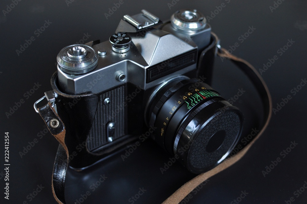 Retro style film photo camera with lens on black background. Front top side view