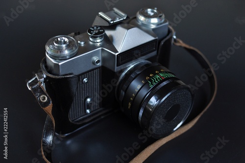 Retro style film photo camera with lens on black background. Front top side view