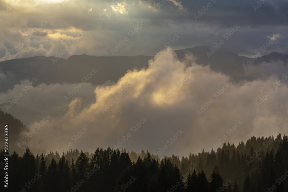 Dramatic rain clouds and thick mist at sunset, in the mountains, in summer Dramatic rain clouds and thick mist at sunset, in the mountains, in summer