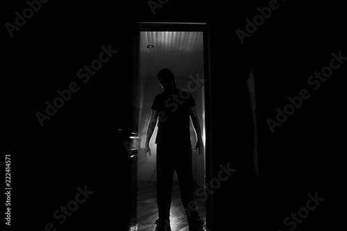 Silhouette of an unknown shadow figure on a door through a closed glass door. The silhouette of a human in front of a window at night. Scary scene halloween concept