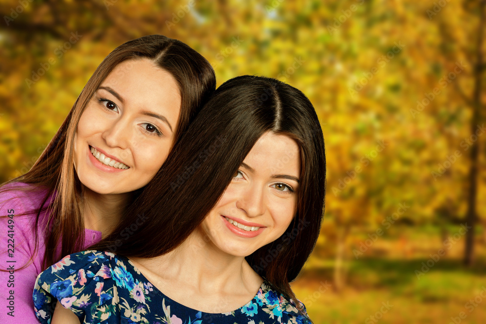 Obraz premium Two cheerful girls twins, in the street autumn park
