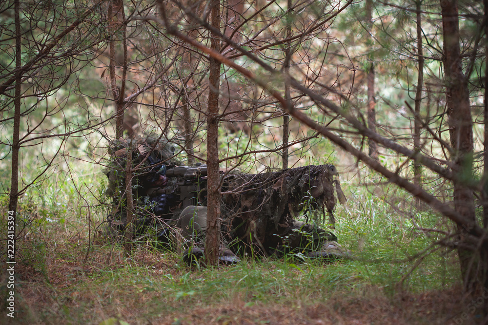 Sniper wearing ghillie camouflage in action Sniper wearing ghillie camouflage in action