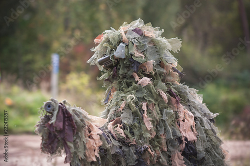 Sniper wearing ghillie camouflage in action photo