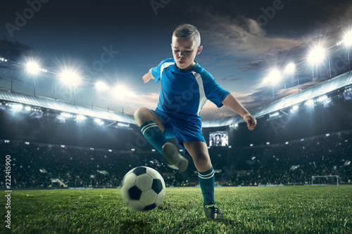 Young boy with soccer ball doing flying kick at stadium. football soccer players in motion on green grass background. Fit jumping boy in action, jump, movement at game. Collage © master1305