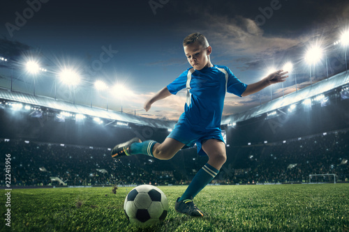 Young boy with soccer ball doing flying kick at stadium. football soccer players in motion on green grass background. Fit jumping boy in action, jump, movement at game. Collage © master1305