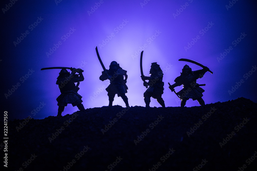 Medieval battle scene with cavalry and infantry. Silhouettes of figures as separate objects, fight between warriors on dark toned foggy background. Night scene. Selective focus
