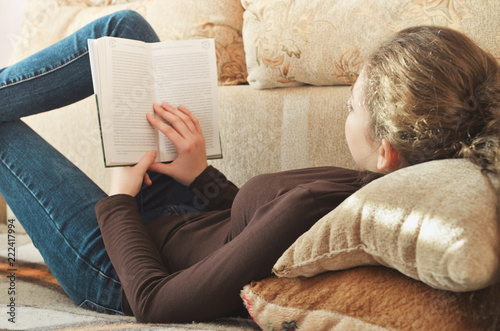 Young Cute Female Student reading a book on the couch