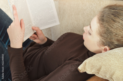 Casual teen girl at home reading a book