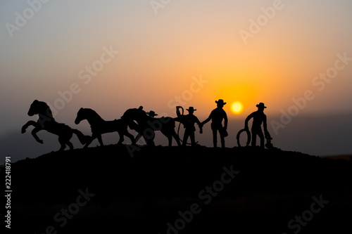Cowboy concept. Silhouette of Cowboys at sunset time. A cowboy silhouette on a mountain with an yellow sky. © zef art
