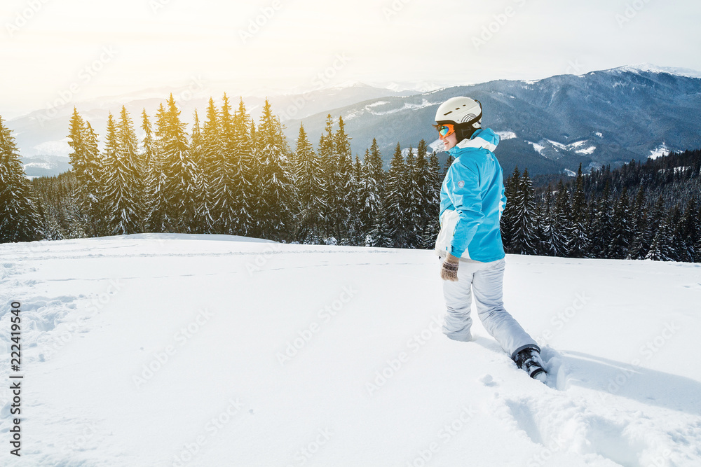 Woman skier in a white and blue suit at the mountain top in snow