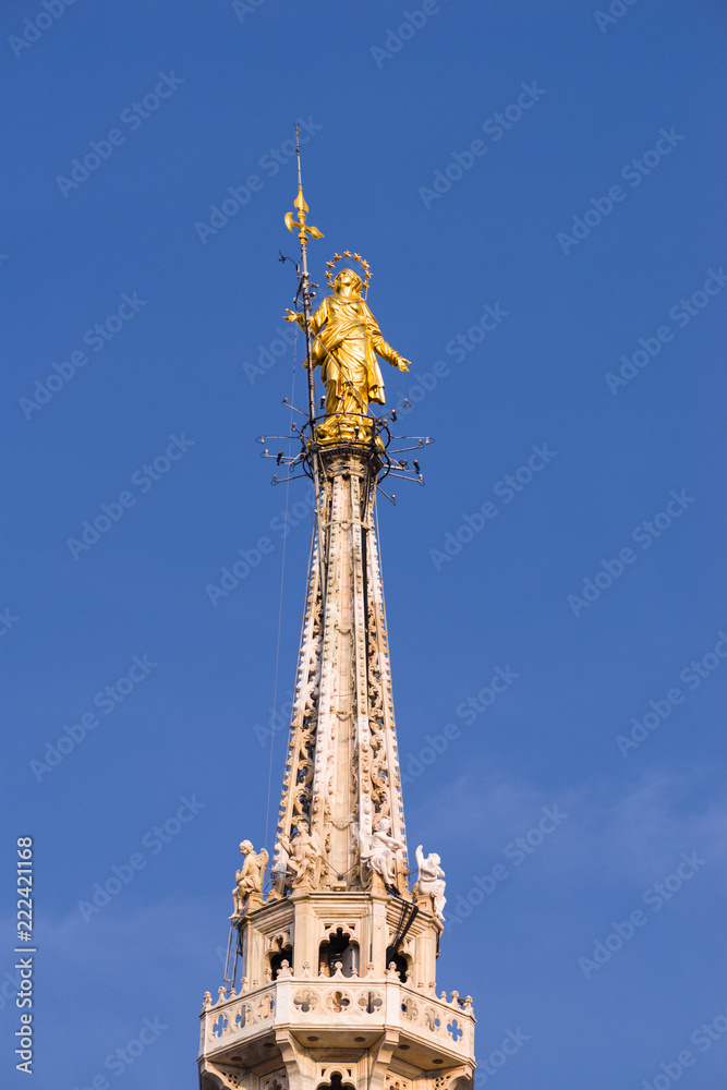 Vertical: Rooftop view of golden statue of St Mary, the highest spire on the rooftop of the Duomo di Milano Vertical: Rooftop view of golden statue of St Mary, the highest spire on the rooftop of the Duomo di Milano
