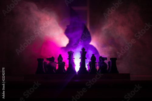 Man playing chess. Scary blurred silhouette of a person at the chessboard with chess figures. Dark toned foggy background. © zef art