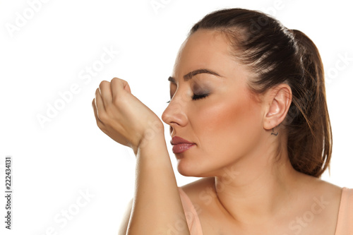 Beautiful woman smelling her wrist on white background