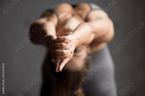 Young sporty woman practicing yoga, doing Ustrasana exercise, Camel pose, working out, wearing sportswear, grey pants, indoor, body close up view, yoga studio, focus on fingers. Well being concept