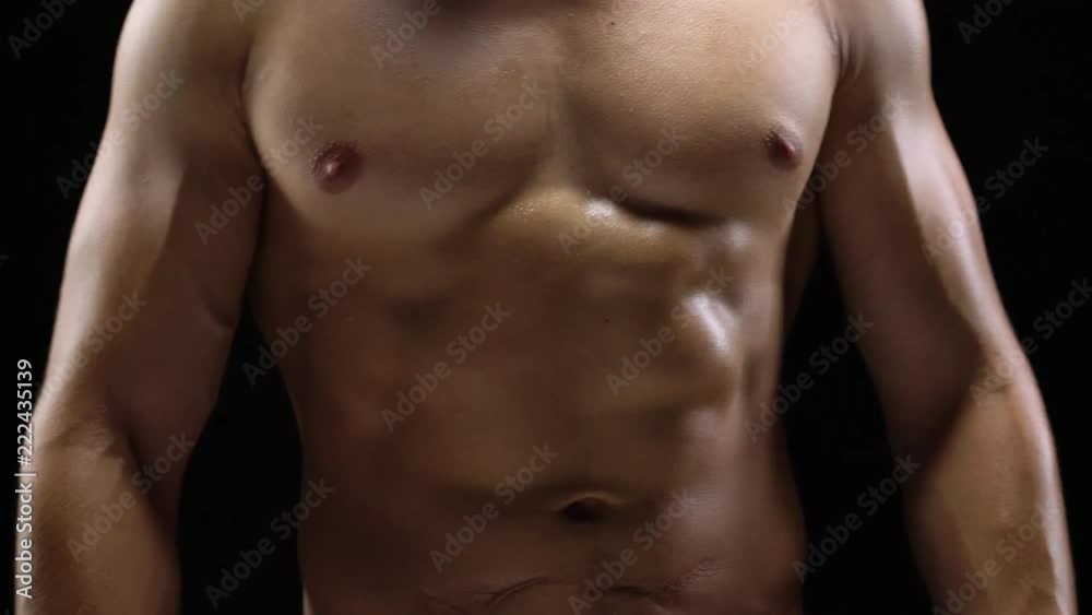 Man shows a muscular strong body close-up on a black background Man shows a muscular strong body close-up on a black background