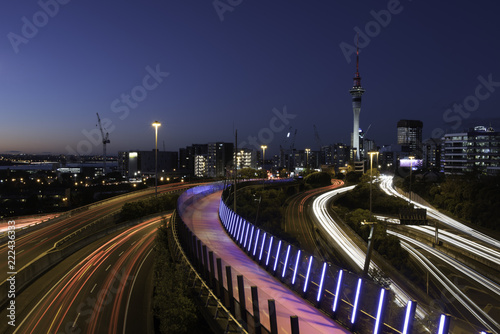 Night view of Auckland City from Hopetoun Street bridge with the motorway junction complex and pink bike path in the foreground. Auckland, New Zealand.