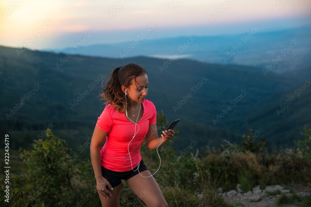Woman trail runner running with smartphone and earphones.