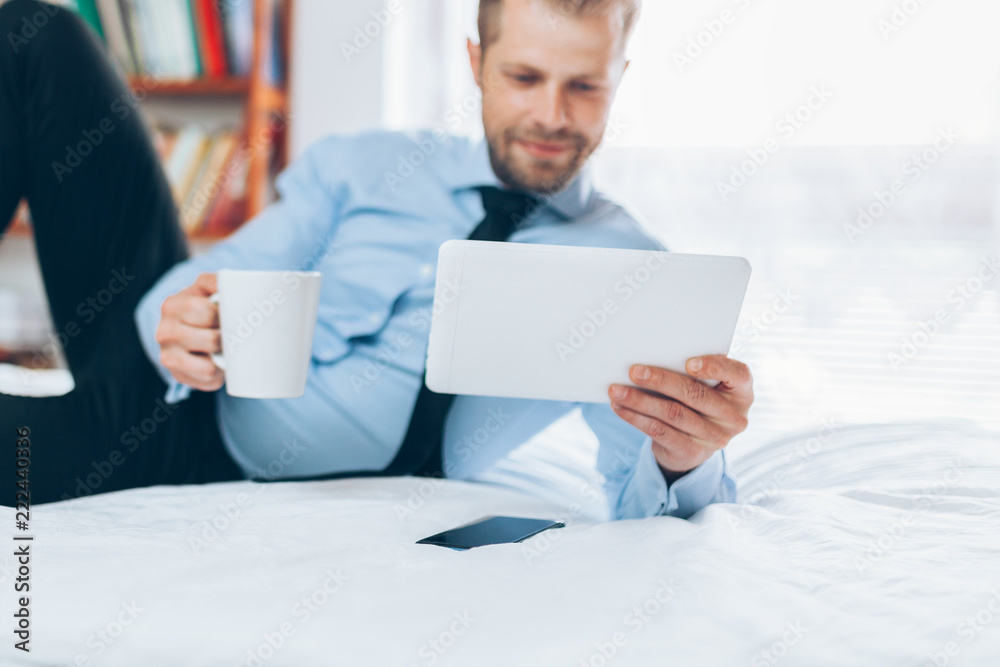 Businessman on bed working with a tablet from his hotel room Businessman on bed working with a tablet from his hotel room