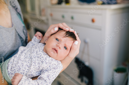 Portrait of mother holding adorable baby girl in hands at home .