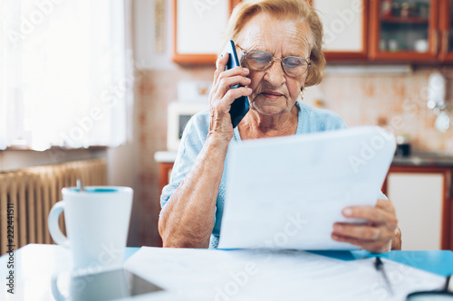 Elderly woman contacting custumer services after recieving a bill photo