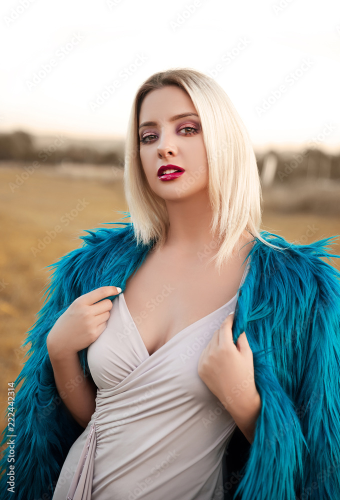Young blonde woman in fur coat and dress outdoors Young blonde woman in fur coat and dress outdoors