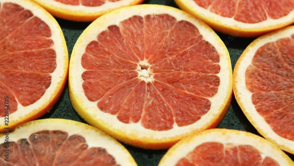 Closeup of composed round slices of cut grapefruit of bright ret color arranged together on glass surface Closeup of composed round slices of cut grapefruit of bright ret color arranged together on glass surface