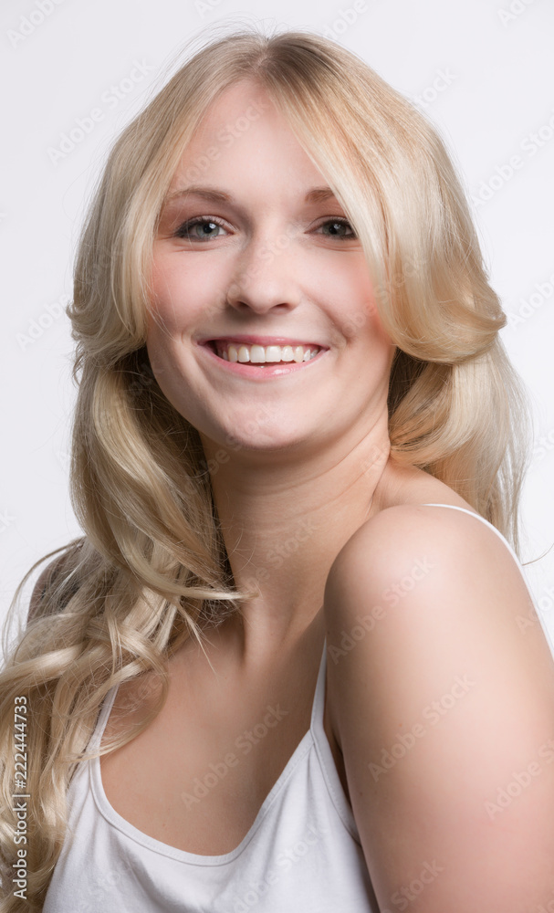 Fototapeta premium Junge hübsche blonde Frau im weissen Shirt lächelt sympathisch