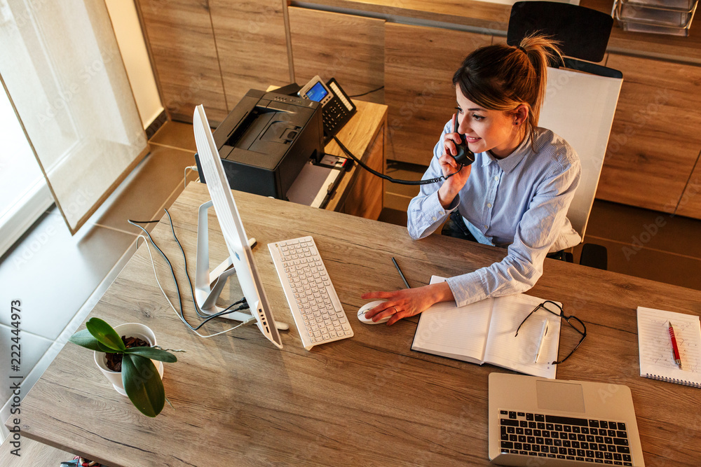© BalanceFormCreative - Businesswoman in her office.She sitting at the desk and talking on the phone.