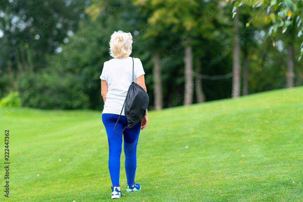 Fit woman carrying a sports bag walking away
