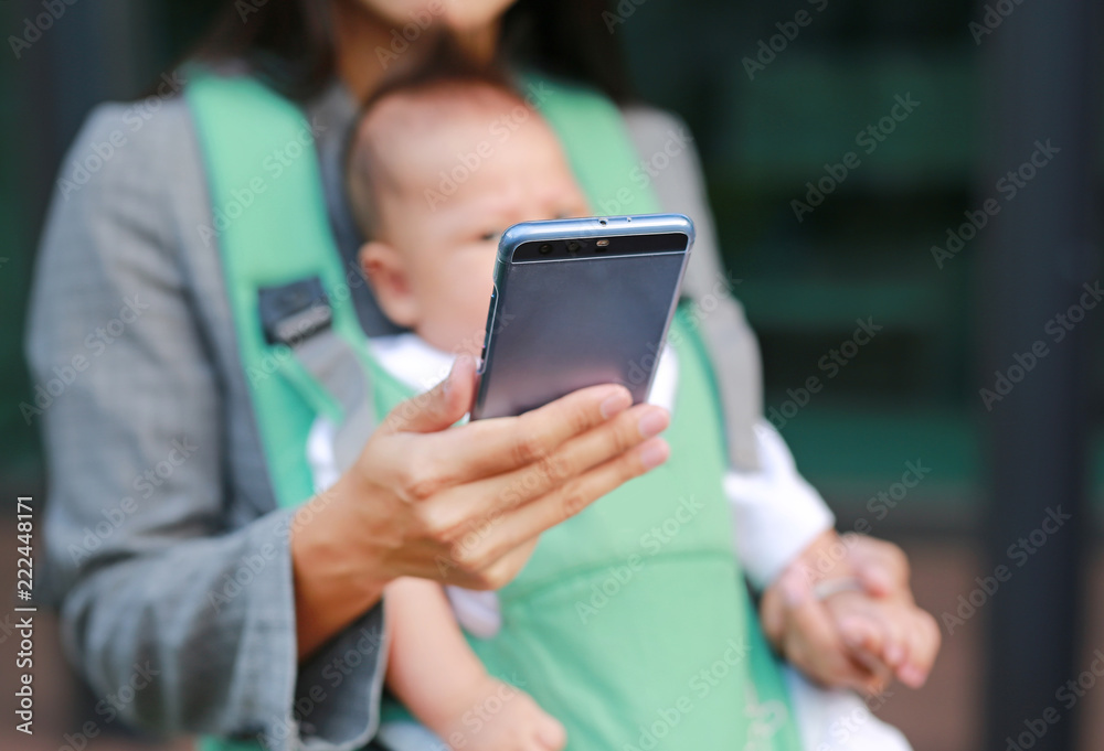 Close up business woman working by telephone with carrying her infant.
