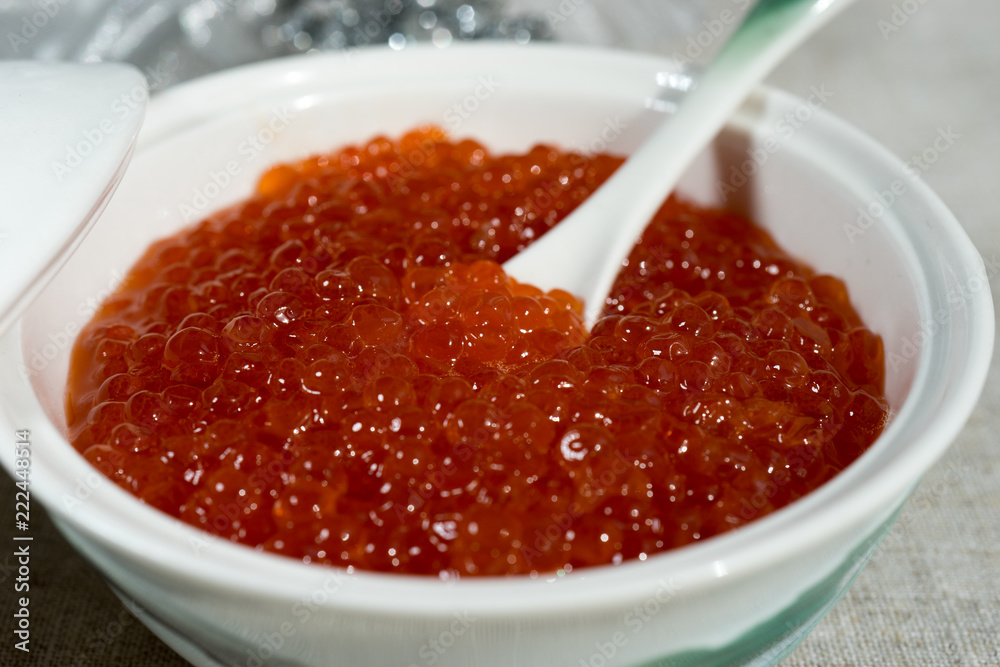 Large red caviar in a beautiful porcelain icon on a gray tablecloth. Large red caviar in a beautiful porcelain icon on a gray tablecloth.