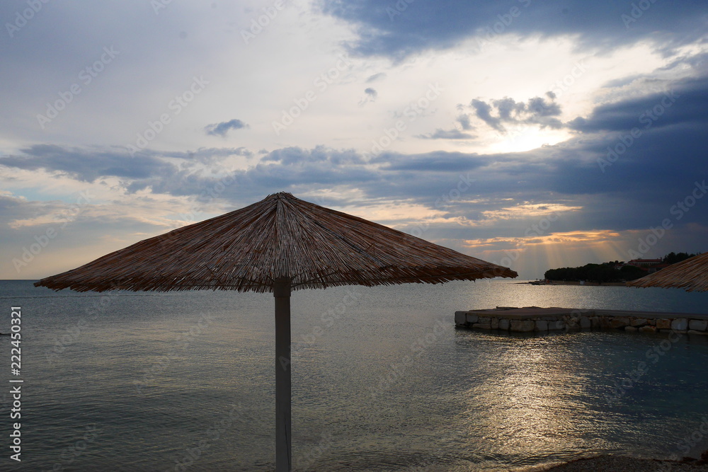 Strandschirm an einem Strand bei Novigrad in Kroatien zur Abendstimmung