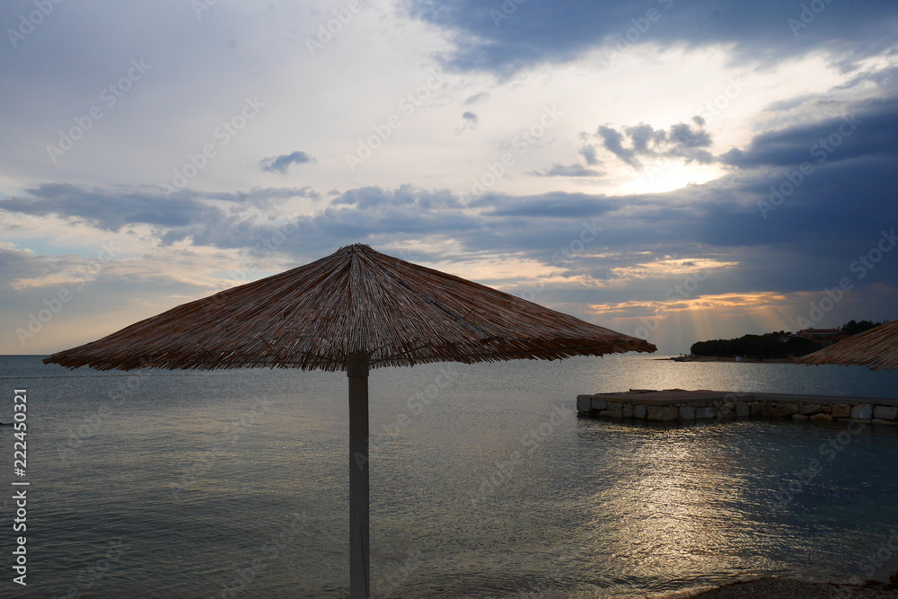 Strandschirm an einem Strand bei Novigrad in Kroatien zur Abendstimmung Strandschirm an einem Strand bei Novigrad in Kroatien zur Abendstimmung