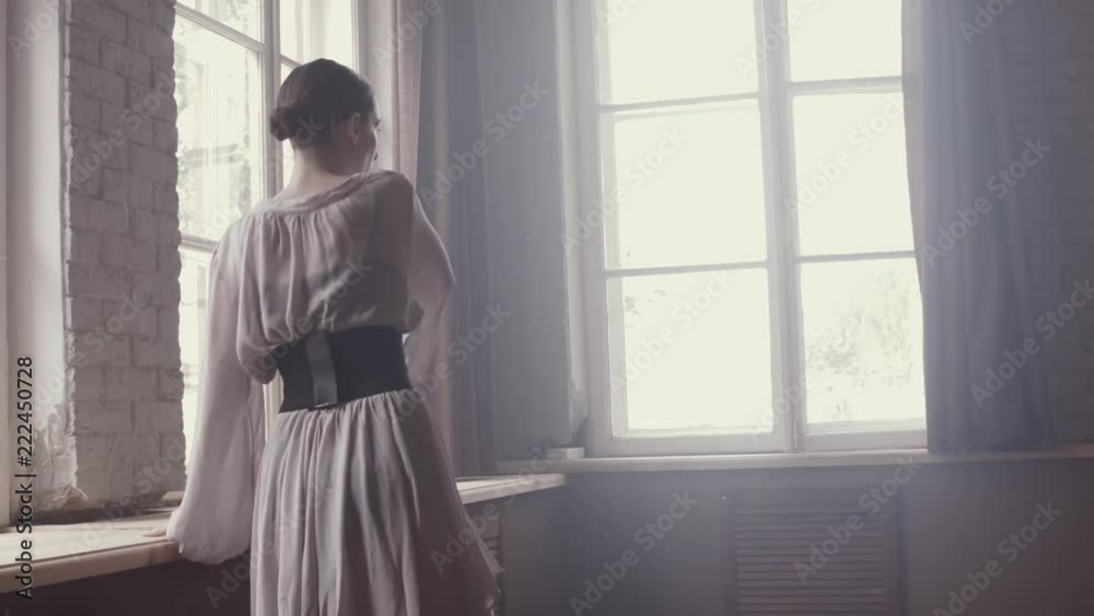 Ballet is dance. Ballerina makes a warm-up at large panoramic window in studio in an antique style. Beautiful airy fashionable dress at ballet dancer. Haze in studio. Plastic and grace of dancer. Ballet is dance. Ballerina makes a warm-up at large panoramic window in studio in an antique style. Beautiful airy fashionable dress at ballet dancer. Haze in studio. Plastic and grace of dancer.