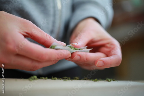 rolled a cigarette with cannabis marijuana by hands. bad habits and addiction