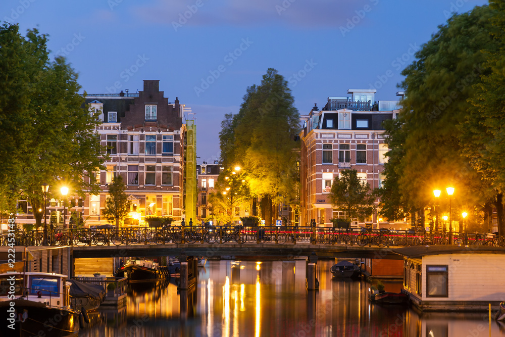Beautiful cityscape of the famous canals of Amsterdam, the Netherlands, at night with a mirror reflection 