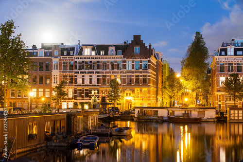 Beautiful cityscape of the famous canals of Amsterdam, the Netherlands, at night with a mirror reflection and a full moon