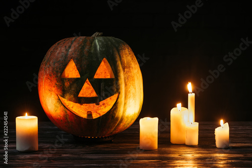 scary jack o lantern with candles on wooden table on black background